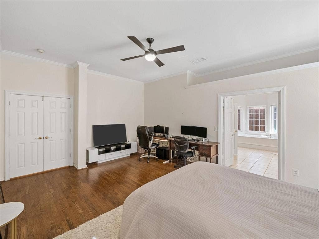 8640 Breakers Point, Dallas, TX 75243 Wood-finish flooring, white double doors, crown molding, ceiling fan, and an open doorway leading to a tiled area with a built-in tub