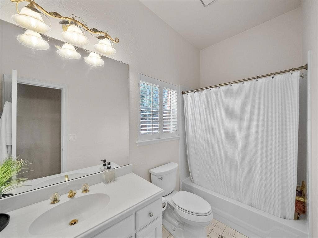 8640 Breakers Point, Dallas, TX 75243 White vanity with an integrated sink, polished brass fixtures, and a large mirror