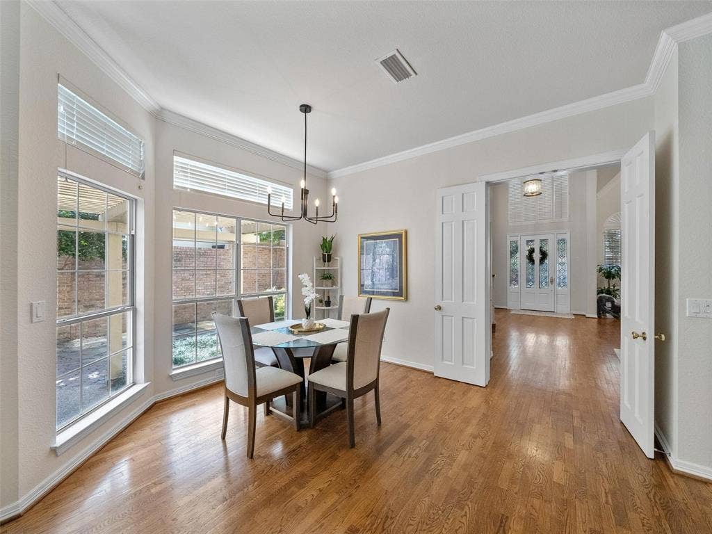 8640 Breakers Point, Dallas, TX 75243 Hardwood flooring throughout, crown molding, double doors, multiple large windows, and a modern chandelier