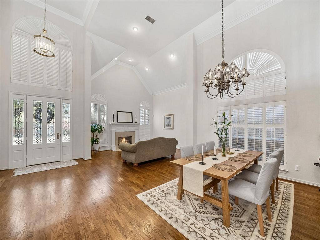 8640 Breakers Point, Dallas, TX 75243 Vaulted ceilings with recessed lighting, wood-finish flooring, fireplace with a mantel, and decorative chandeliers