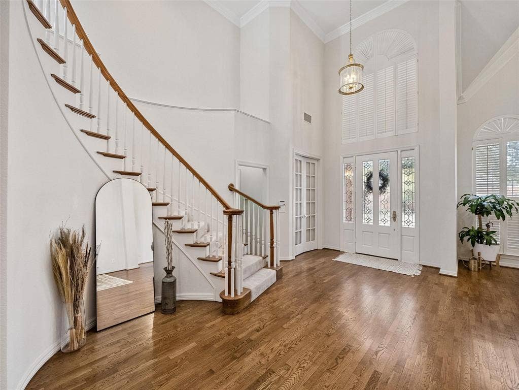 8640 Breakers Point, Dallas, TX 75243 Grand entryway featuring high ceilings, a curved staircase with wood-finish treads, double entry doors with leaded glass, and wood-finish flooring