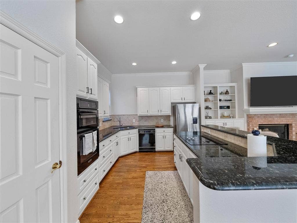 8640 Breakers Point, Dallas, TX 75243 Kitchen featuring white cabinetry, dark stone countertops, stainless steel appliances, wood-finish flooring, and recessed lighting