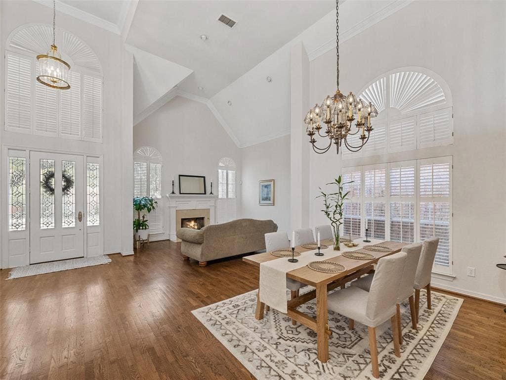 8640 Breakers Point, Dallas, TX 75243 Double-height entry with leaded glass double doors, wood-finish flooring, vaulted ceilings, and a fireplace with a stone surround