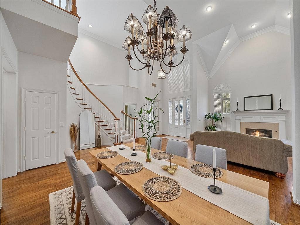 8640 Breakers Point, Dallas, TX 75243 Hardwood flooring throughout, a grand spiral staircase with wood banister, a vaulted ceiling, and a fireplace with a mantel