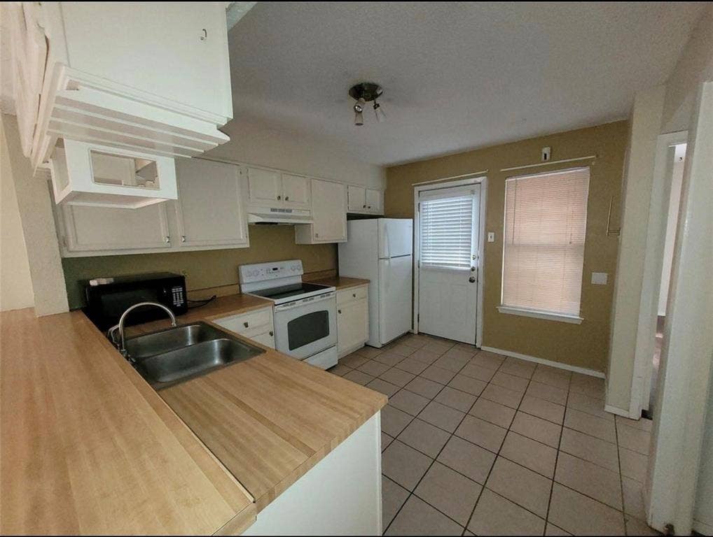 1801 W Spring Creek Parkway, #F2, Plano, TX 75023 Kitchen featuring white cabinetry, wood-finish countertops, stainless steel double-basin sink, and tile flooring