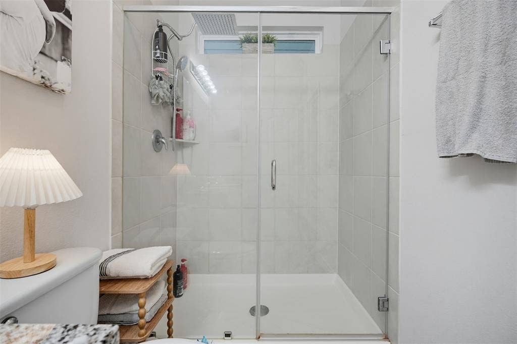 5525 Willamette Drive, Fort Worth, TX 76119 Glass-enclosed shower with white tiled walls and a white shower pan