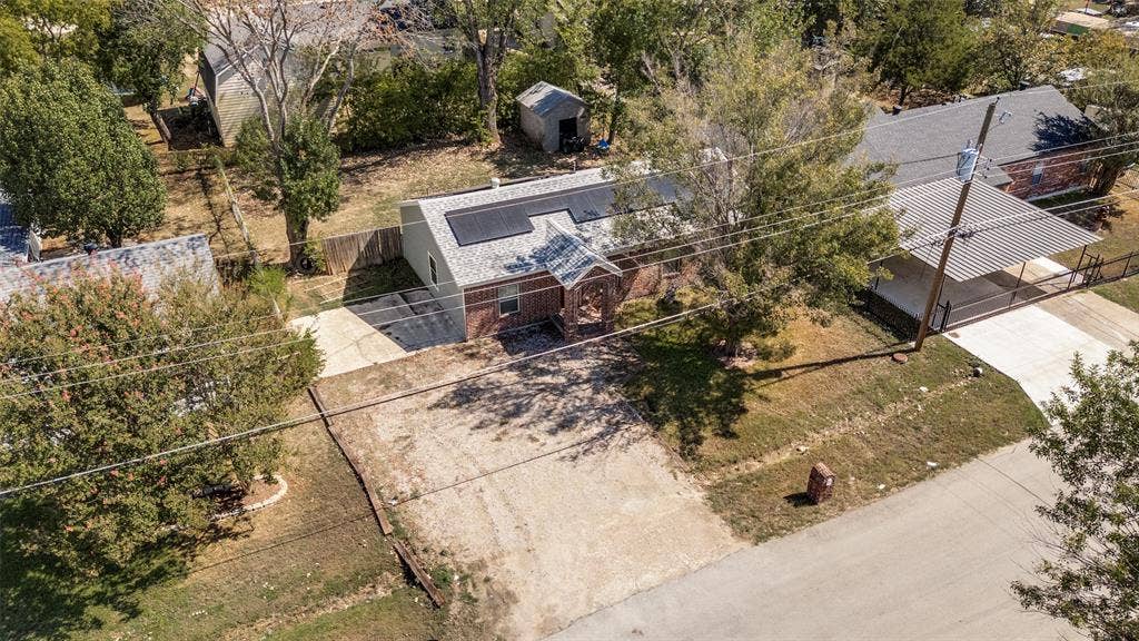 Brick exterior with solar panels, an attached carport, and a detached shed