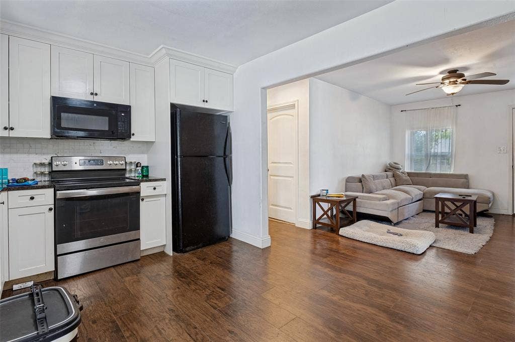 Kitchen featuring white upper and lower cabinetry, dark countertops, stainless steel range, and a built-in microwave