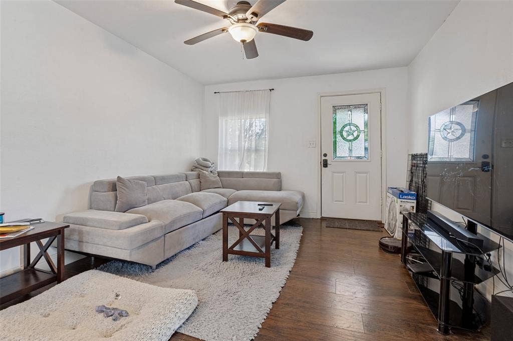 Wood-finish flooring, white walls, ceiling fan with light fixture, and a white entry door with decorative glass inserts