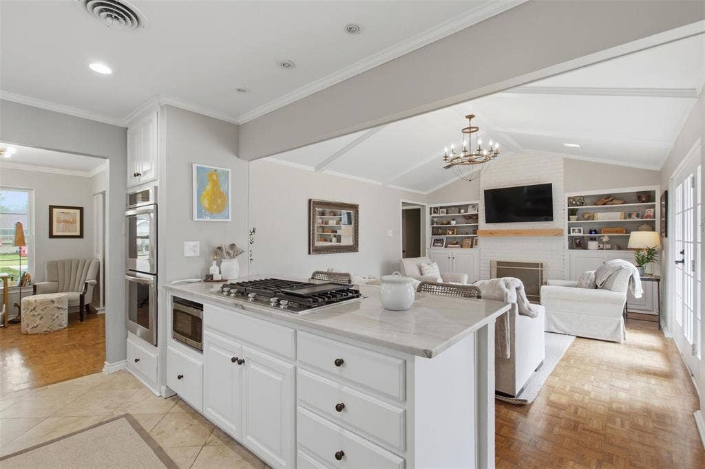 3612 Regent Drive, Dallas, TX 75229 Kitchen island with integrated gas cooktop and white cabinetry, double wall ovens, vaulted ceiling, built-in shelving, and French doors