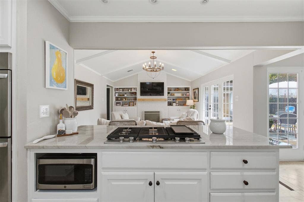 3612 Regent Drive, Dallas, TX 75229 Kitchen island with a built-in cooktop, microwave, and white cabinetry