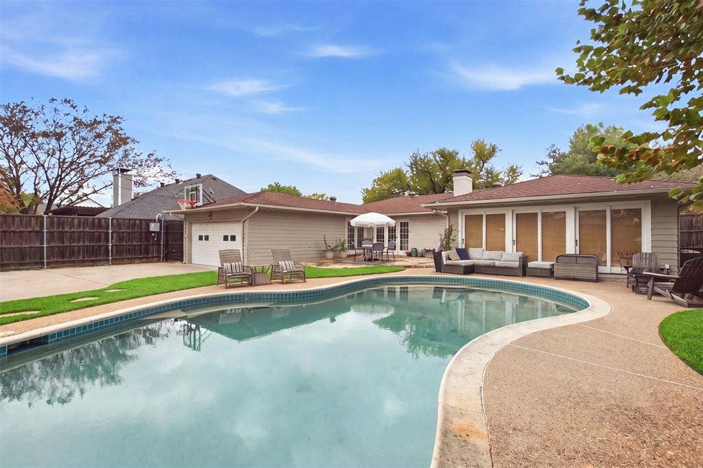 3612 Regent Drive, Dallas, TX 75229 Resort-style backyard featuring a kidney-shaped pool, extensive concrete decking, and a detached two-car garage