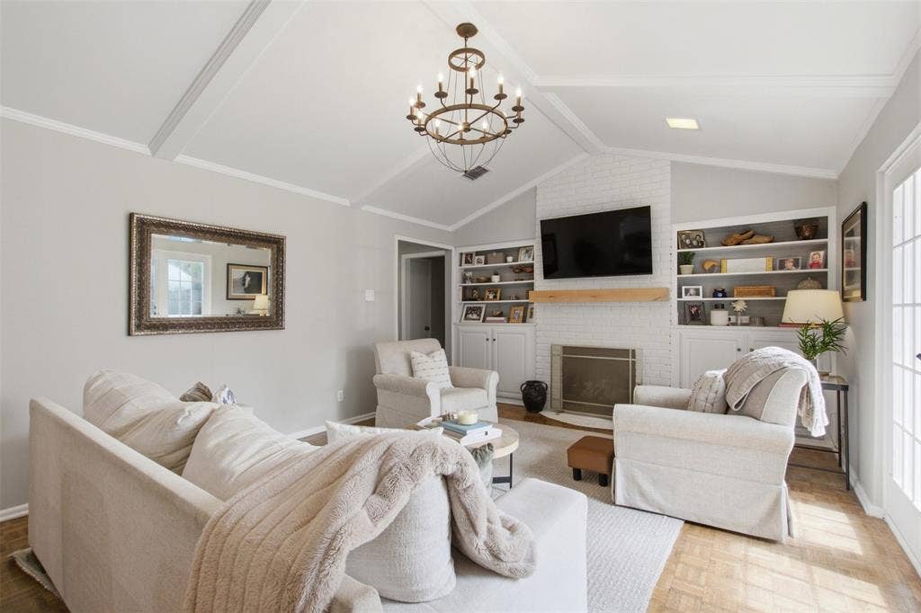 3612 Regent Drive, Dallas, TX 75229 Vaulted ceiling with exposed beams, brick-surround fireplace with wood mantel, built-in shelving, wood-finish flooring, and French doors