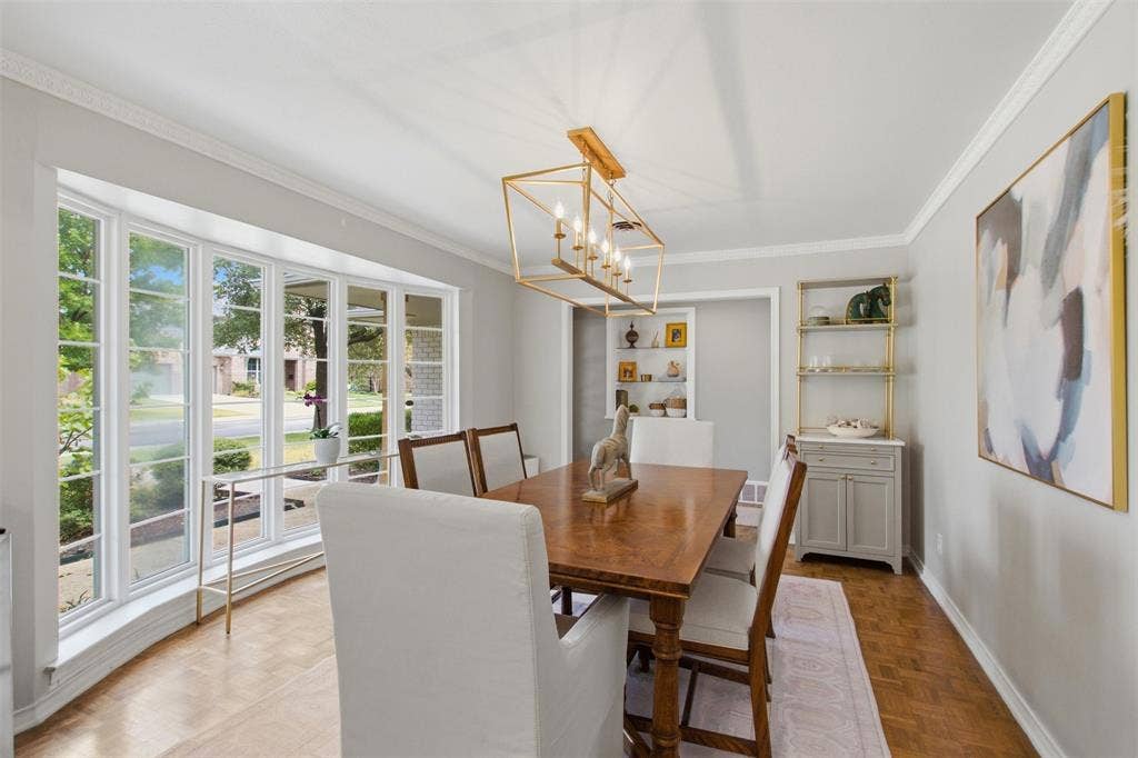 3612 Regent Drive, Dallas, TX 75229 Bay window with multiple panes, crown molding, wood-finish flooring, built-in shelving, and a decorative chandelier