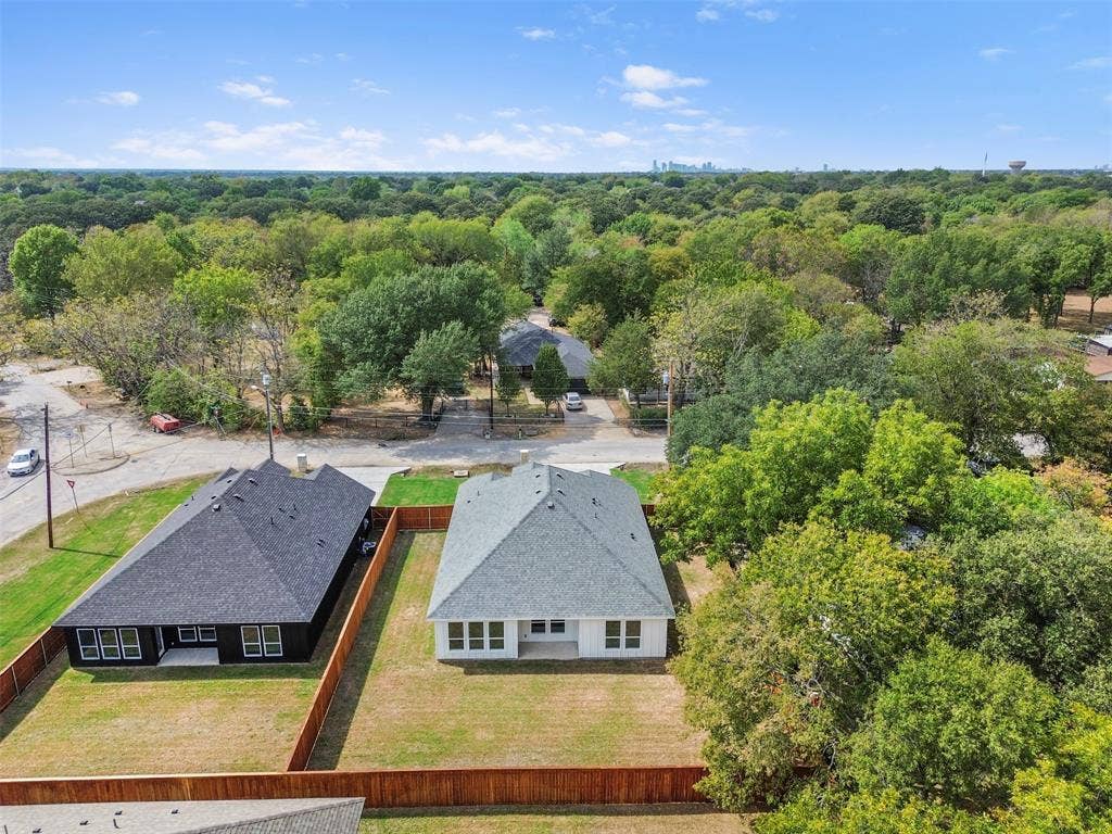 Expansive property featuring a newly constructed residence with a light gray shingle roof, a surrounding wood fence, and a large grass yard