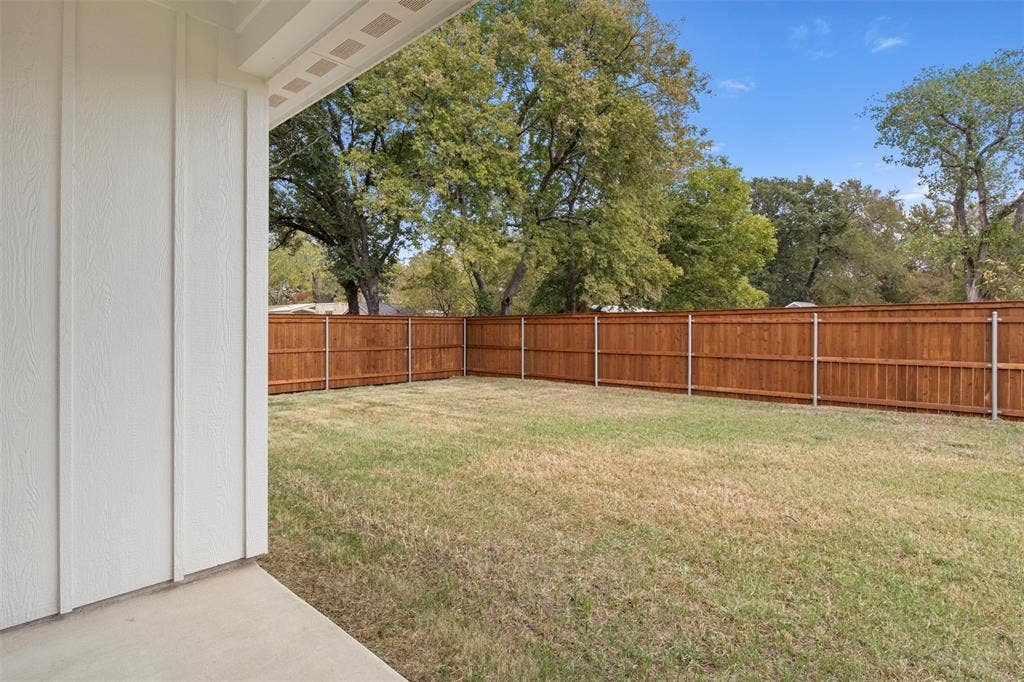 Expansive backyard featuring a stained wood privacy fence, concrete patio, and mature trees