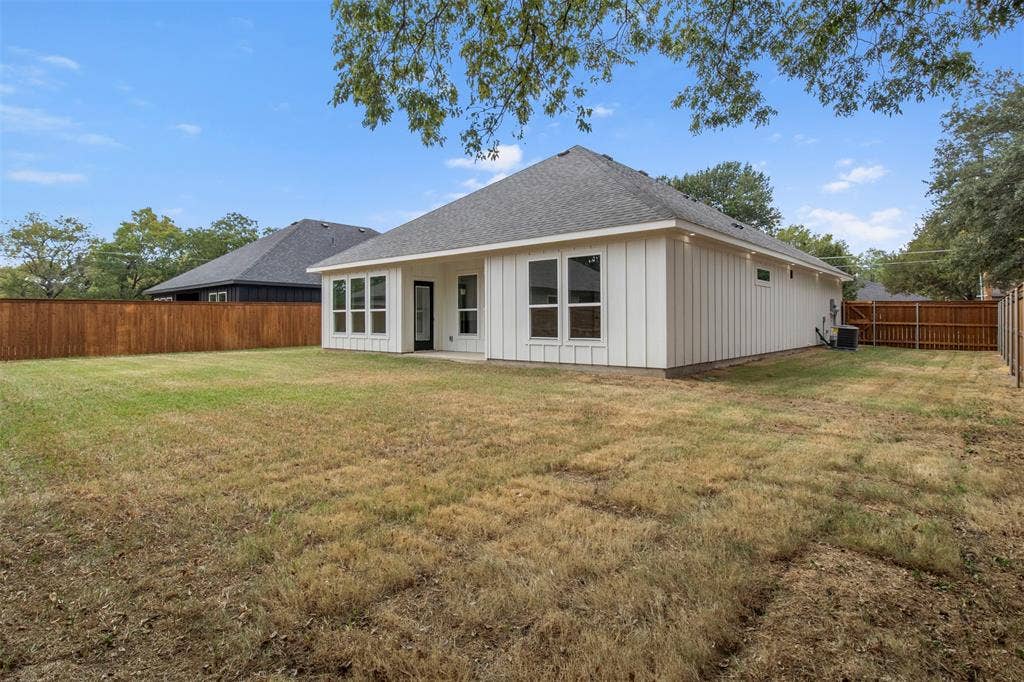Expansive backyard featuring a wood privacy fence, a concrete patio, and multiple large windows