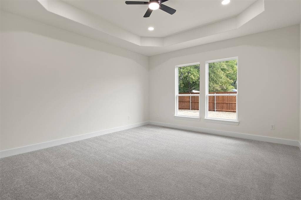 Spacious room featuring a tray ceiling, recessed lighting, and a ceiling fan
