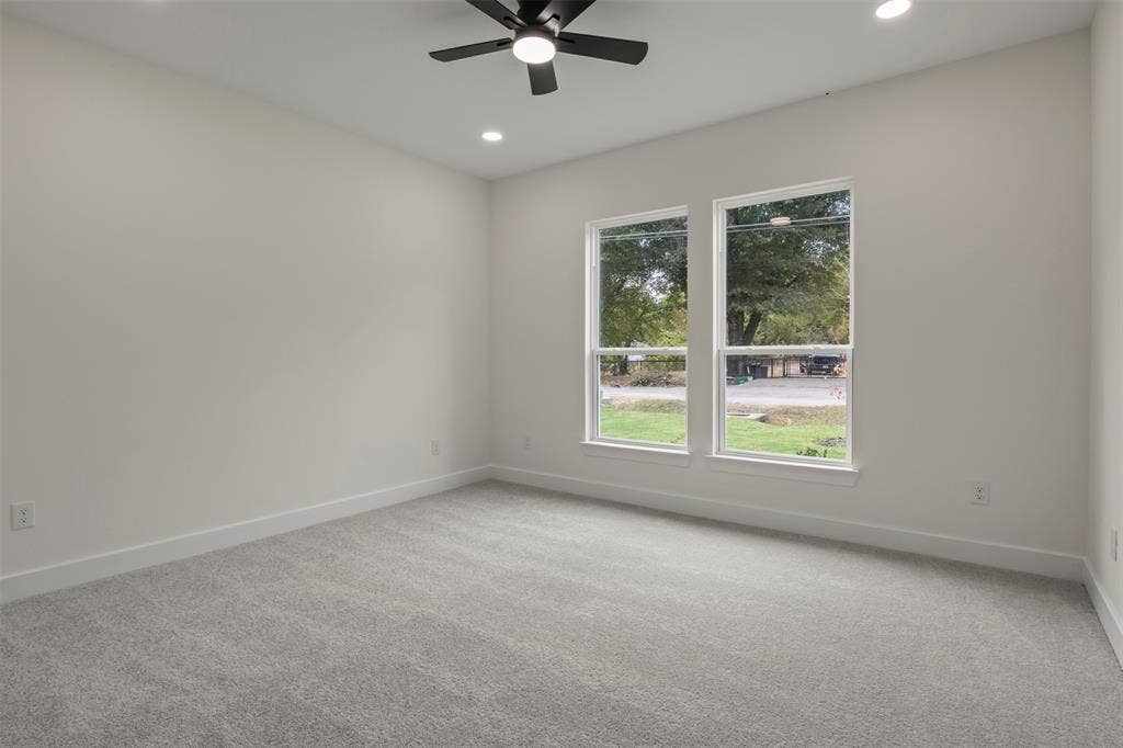 Spacious room featuring two large windows, recessed lighting, a ceiling fan, and light gray carpeting