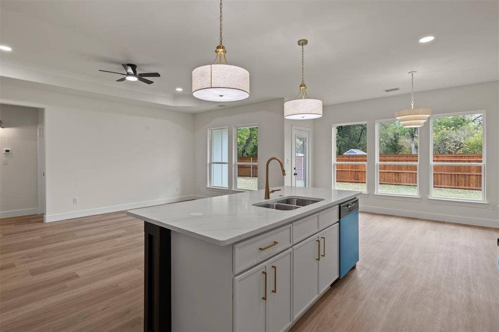 Kitchen island with an undermount double basin sink, brass-finish faucet, and white cabinetry with gold-tone hardware