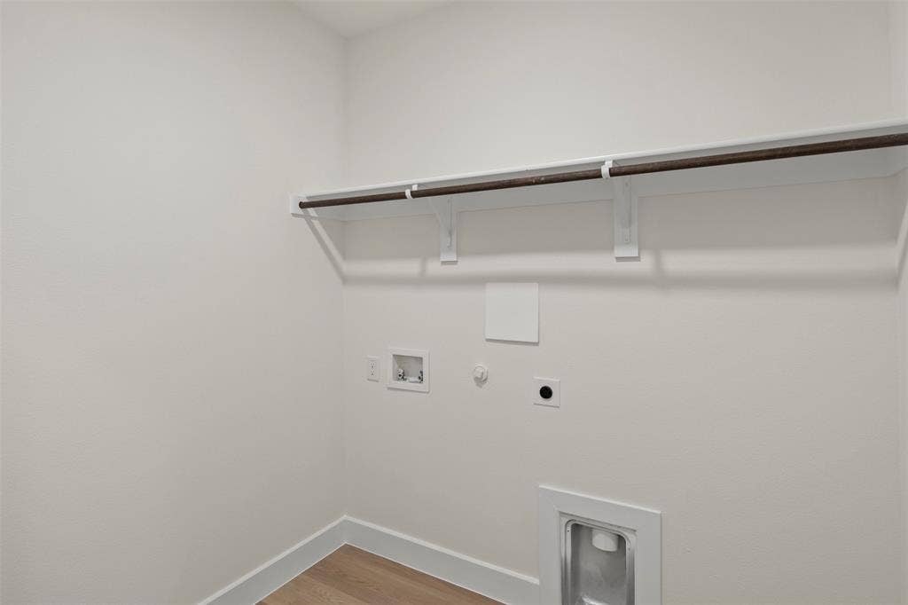 Laundry space featuring a hanging rod, utility connections, and wood-finish flooring