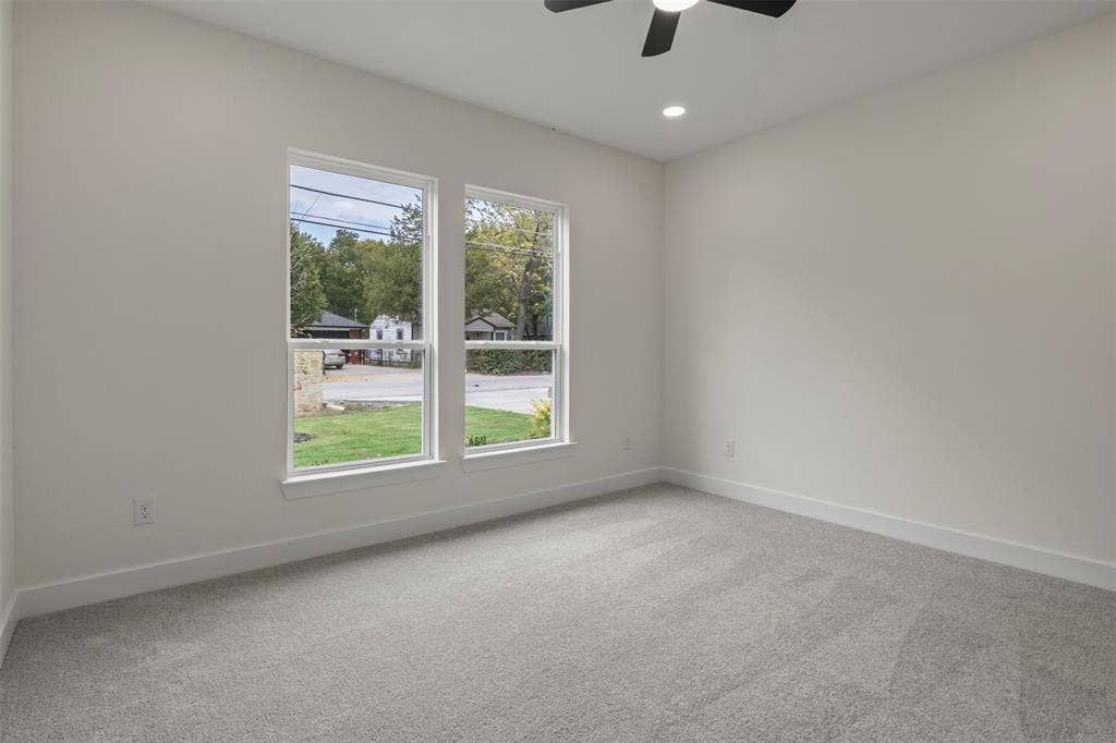 Neutral wall paint with two large windows, recessed lighting, and a ceiling fan