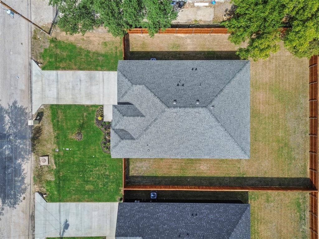 Single-story residence featuring a gray shingle roof, concrete driveway, and a fenced backyard