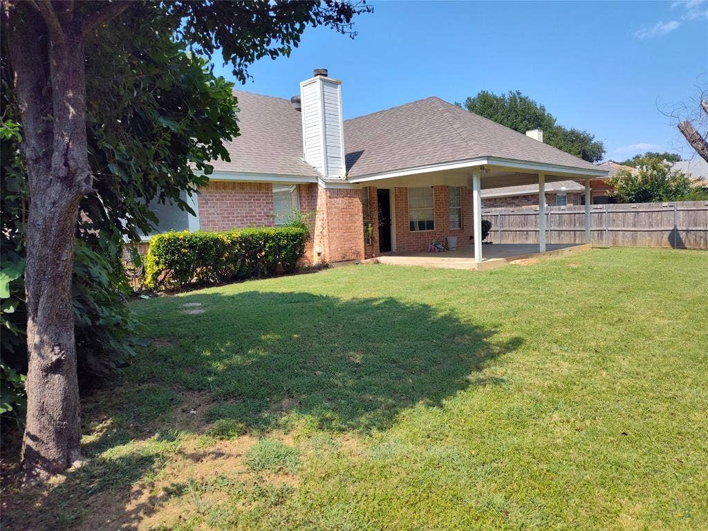 Brick exterior featuring a covered patio, exterior chimney, and fenced backyard