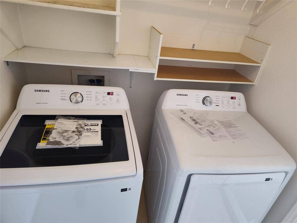 Laundry area featuring white top-loading washer and front-loading dryer, complemented by built-in white shelving