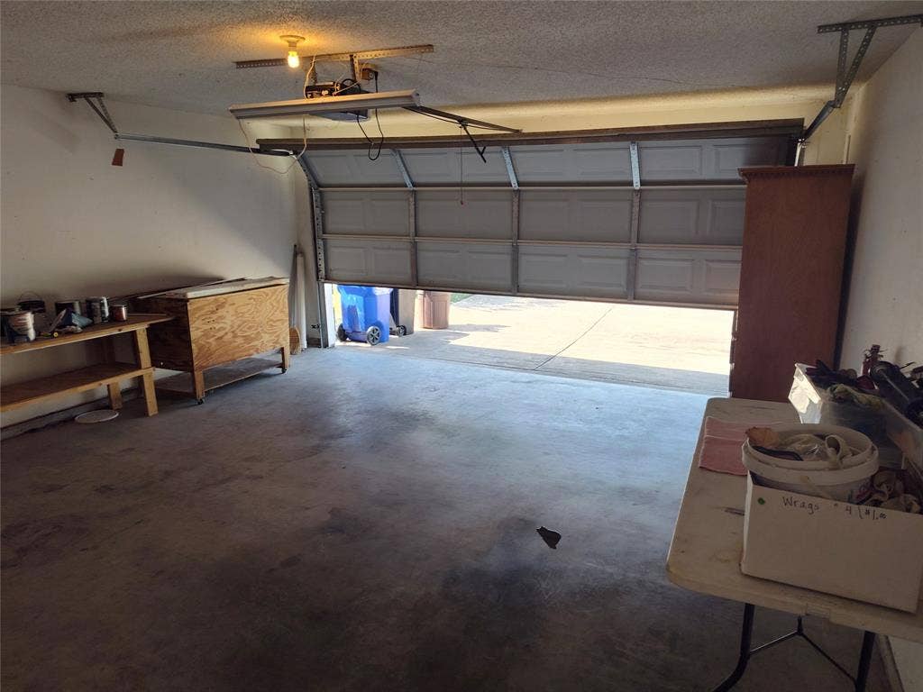 Attached multi-car garage featuring a concrete floor, sectional overhead door, and automated garage door opener
