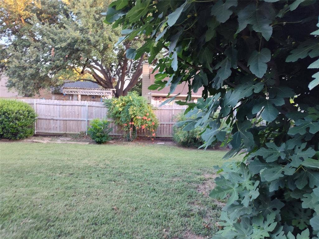 Backyard featuring a manicured lawn, wood privacy fencing, and mature landscaping