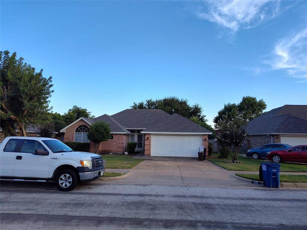 Single-story brick exterior featuring a multi-gable roofline, arched window, and two-car garage with a concrete driveway