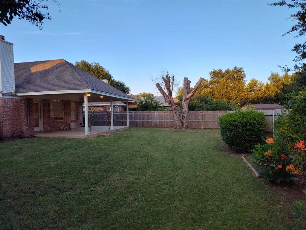 Covered patio with recessed lighting, brick exterior, fenced backyard, and mature landscaping