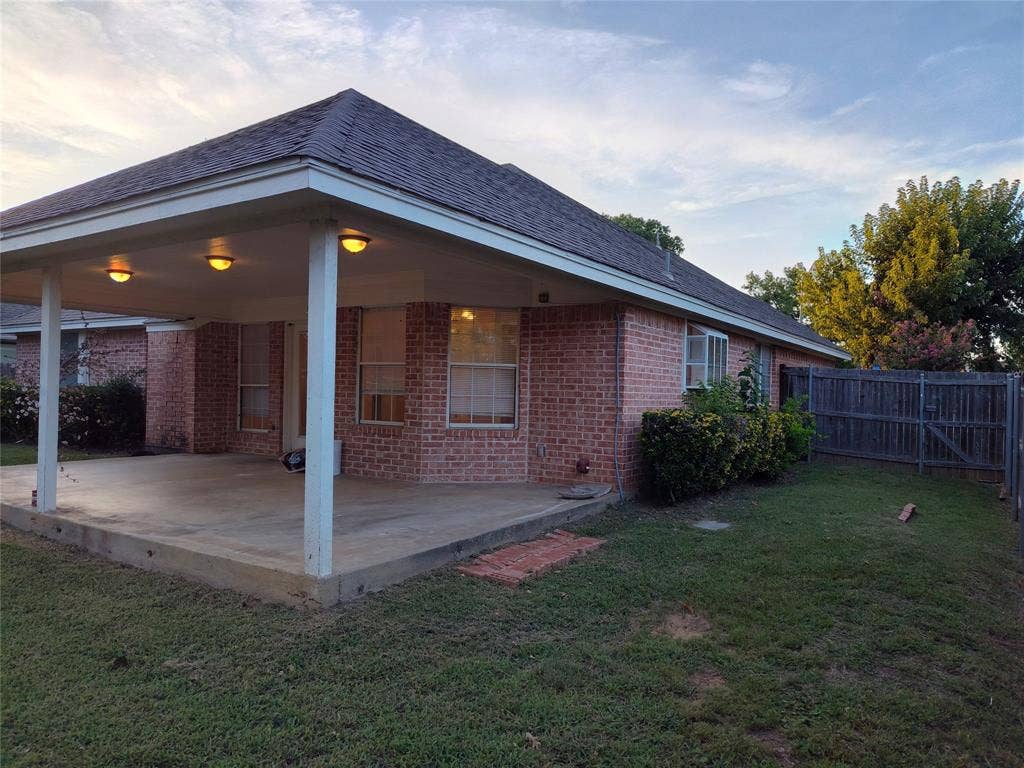 Covered concrete patio with recessed lighting, brick exterior, hip roof, and fenced backyard