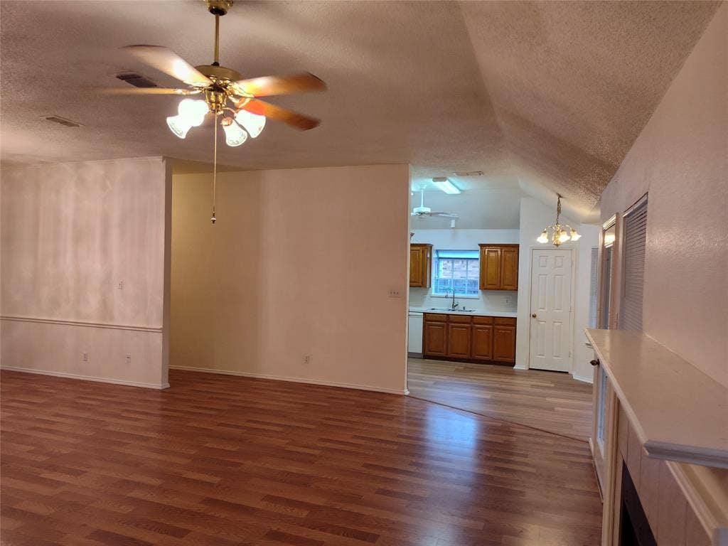 Wood-finish flooring, vaulted ceilings, multi-light ceiling fan, and traditional cabinetry