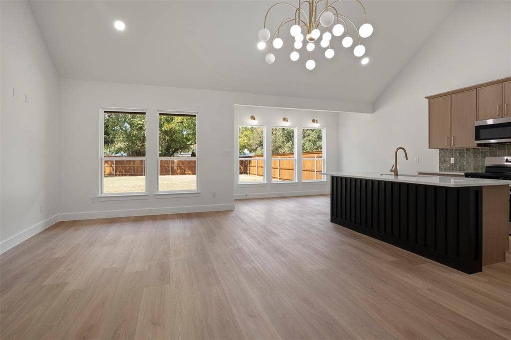 2507 Picadilly Boulevard, Mesquite, TX 75149 Vaulted ceiling with an orb chandelier, wood-finish flooring, a kitchen island with a white countertop, and expansive windows