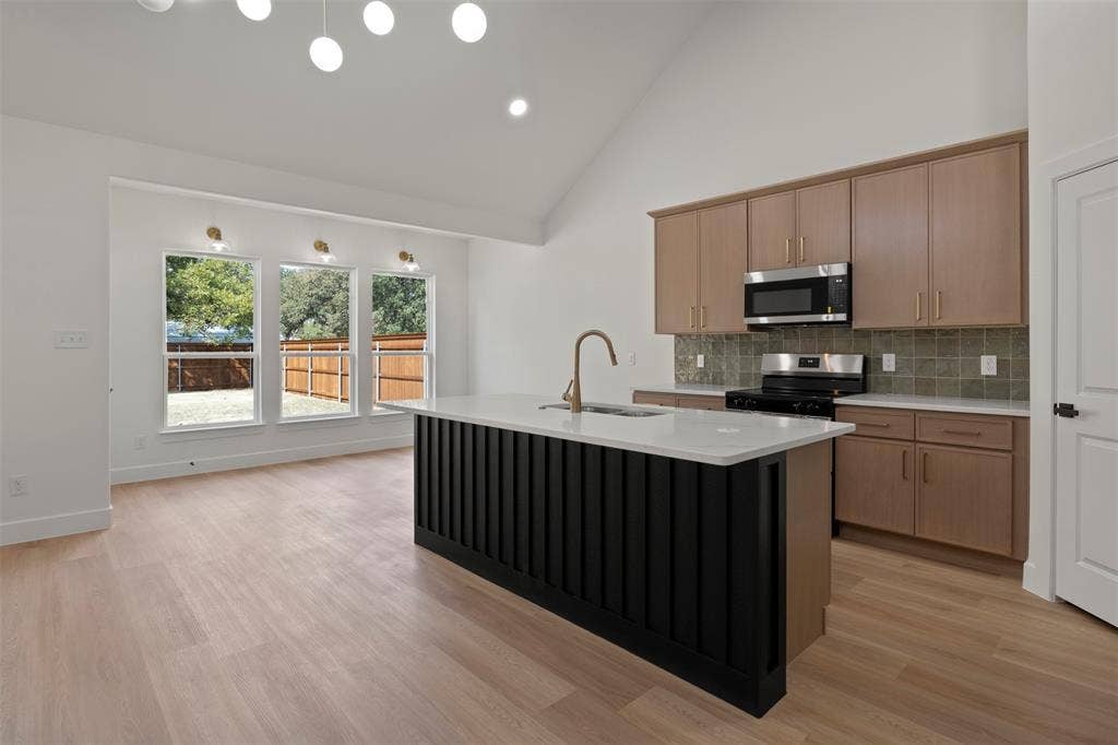 2507 Picadilly Boulevard, Mesquite, TX 75149 Open-concept living space featuring wood-finish flooring, a kitchen island with a white countertop, and stainless steel appliances