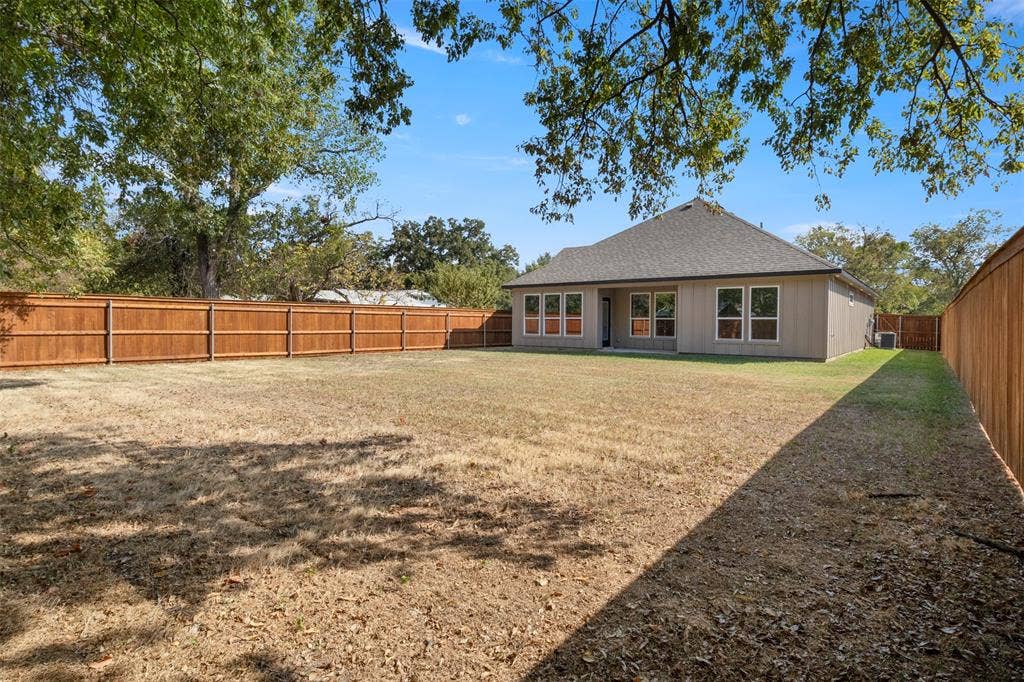 2507 Picadilly Boulevard, Mesquite, TX 75149 Expansive rear yard with privacy fencing and a detached residential structure featuring a shingled roof and multiple windows