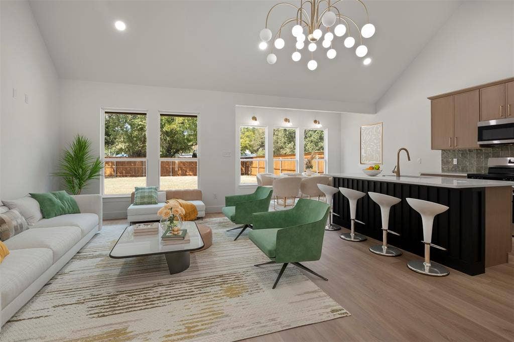 2507 Picadilly Boulevard, Mesquite, TX 75149 Vaulted ceiling with a contemporary chandelier, light wood-finish flooring, kitchen island with seating, stainless steel appliances, and large windows