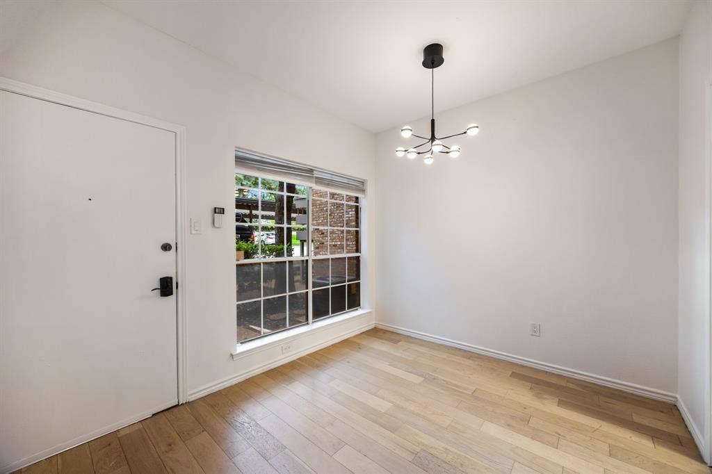 9801 Royal Lane, #701, Dallas, TX 75231 Wood-finish flooring, white walls, and a contemporary multi-bulb chandelier