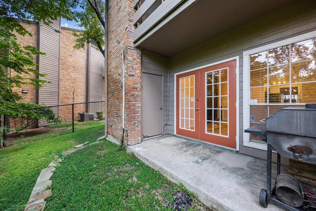 9801 Royal Lane, #701, Dallas, TX 75231 Red-framed French doors, large picture window, and a concrete patio space