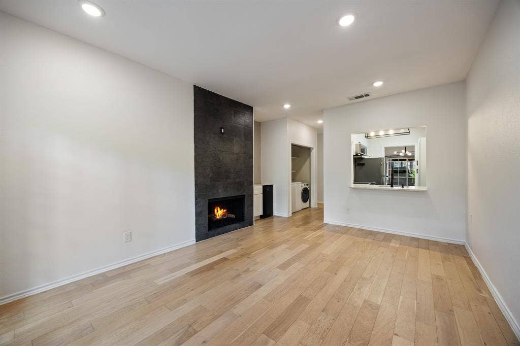 9801 Royal Lane, #701, Dallas, TX 75231 Wood-finish flooring, recessed lighting, and a modern fireplace with a dark stone-look surround