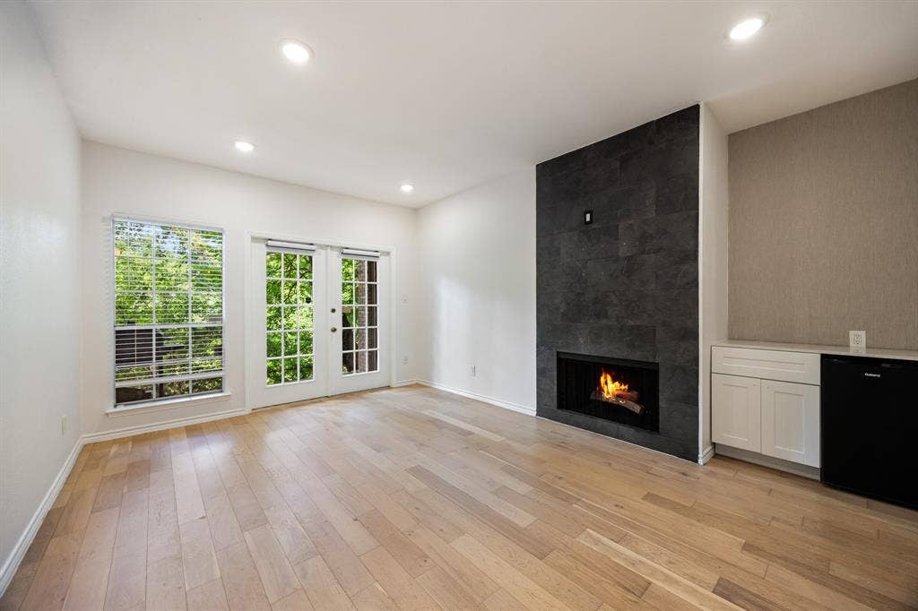 9801 Royal Lane, #701, Dallas, TX 75231 Light wood-finish flooring, recessed lighting, and a dark tile fireplace with an integrated firebox