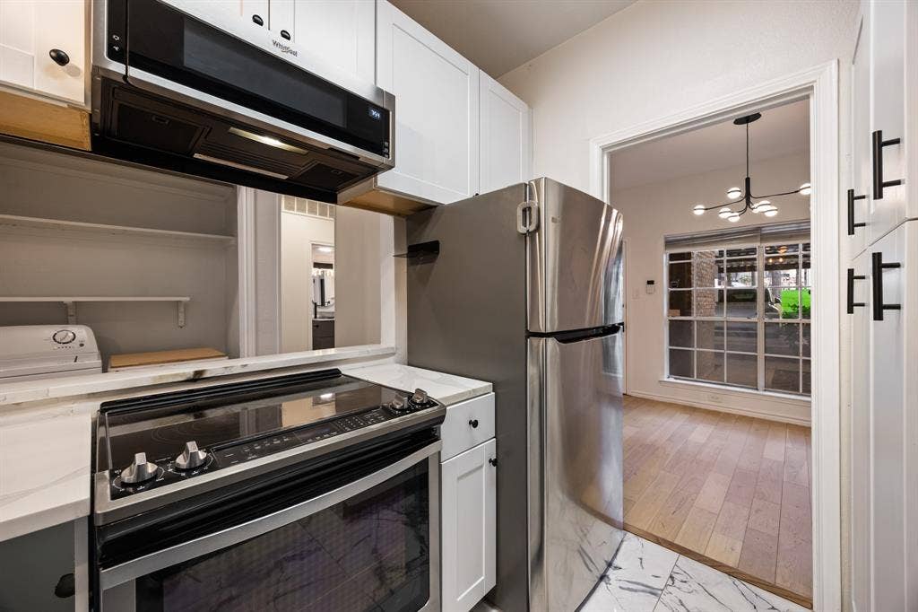 9801 Royal Lane, #701, Dallas, TX 75231 White cabinetry, stainless steel appliances, electric range, quartz countertops, and marble-finish tile flooring