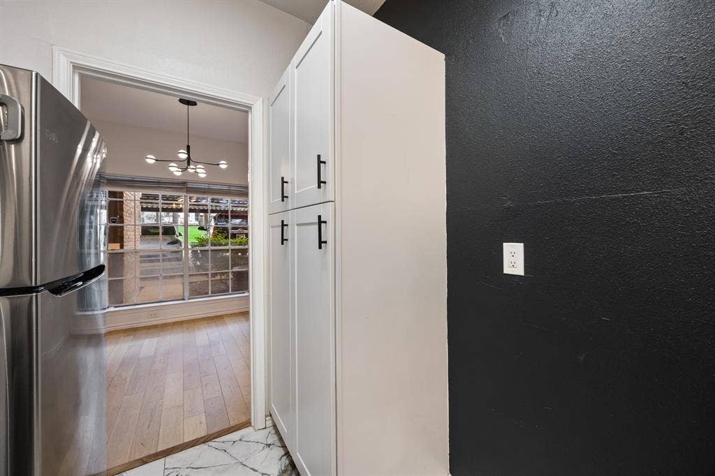 9801 Royal Lane, #701, Dallas, TX 75231 Stainless steel refrigerator, white shaker-style cabinetry with black hardware, and patterned floor tile