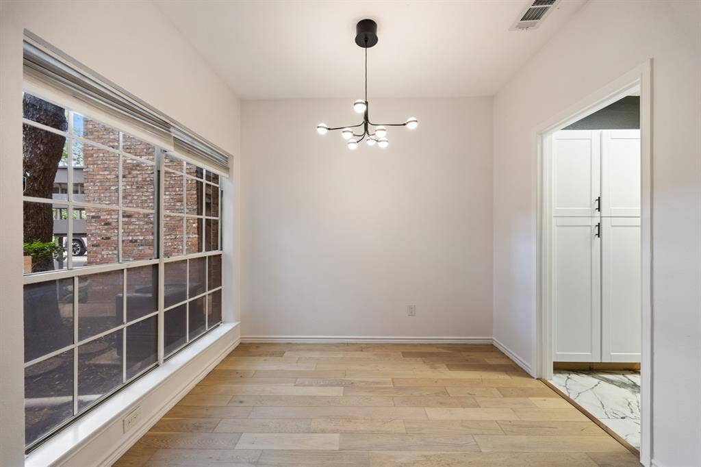 9801 Royal Lane, #701, Dallas, TX 75231 Expansive window with grid panes, wood-finish flooring, contemporary ceiling fixture, white walls, and built-in white cabinetry with black hardware