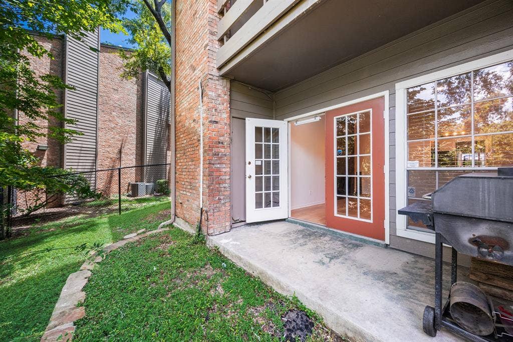 9801 Royal Lane, #701, Dallas, TX 75231 Private patio with concrete surface, double French doors, large windows, and a brick exterior accent
