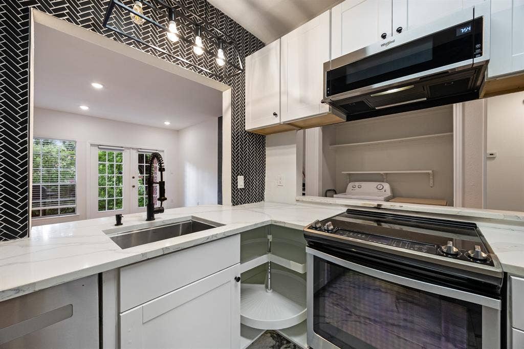 9801 Royal Lane, #701, Dallas, TX 75231 White shaker cabinetry, stainless steel sink, black herringbone tile backsplash, white countertops, and contemporary overhead lighting