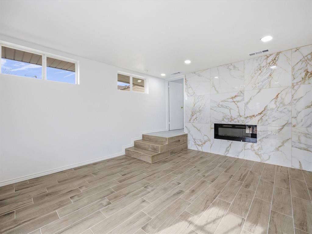 10270 Kilkenny Place, Dallas, TX 75228 Expansive room featuring wood-finish flooring, a built-in electric fireplace with a large format tile surround, recessed lighting, and multiple windows