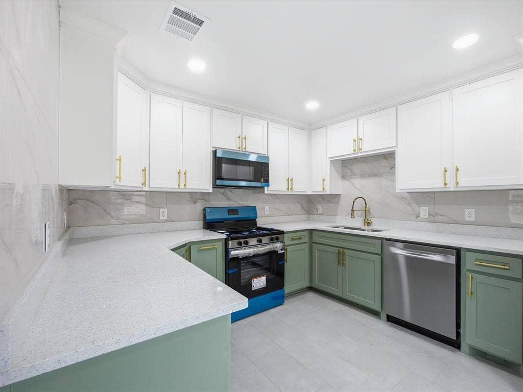10270 Kilkenny Place, Dallas, TX 75228 Contemporary kitchen featuring two-tone cabinetry with gold-tone hardware, white speckled countertops, an undermount sink with a gold-tone faucet, and a tile backsplash